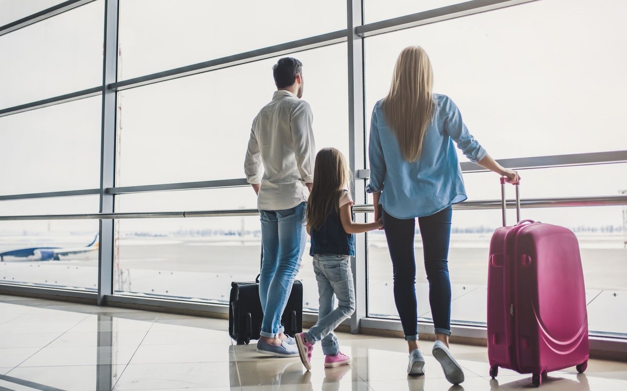 Family in airport. Attractive young woman, handsome man and their cute little daughter are ready for traveling! Happy family concept.; Shutterstock ID 1033801309; Projektnummer (Pxxxx): P4077 ; Kunde/Lizenznehmer: Ergo Group AG ; Job/Projekt: AN-18-1736; Ansprechperson Roba: Catja Vetter